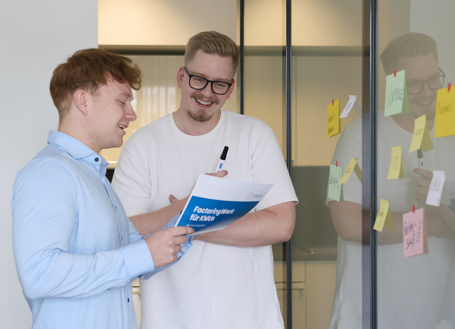 Zwei junge Männer lesen und diskutieren über Factoringwerk für kmus