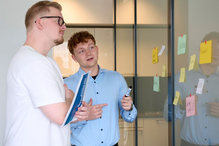 Zwei junge Männer lesen und diskutieren über Factoringwerk für kmus